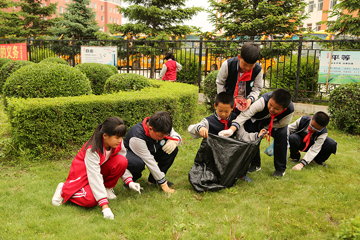 09学生们在绿化带认真清除白色垃圾，草坪上的杂物.jpg